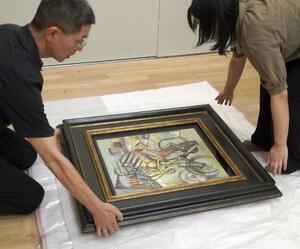 贋作と判断した油彩画「自転車乗り」を梱包する徳島県立近代美術館の学芸員=7月、徳島市