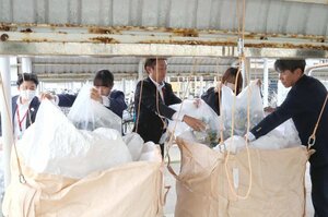 家庭で出た空き缶を荒川中の保管場所に運び込む新潟県信用組合の職員たち=村上市坂町