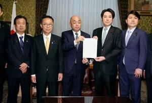 　衆院の築山信彦事務総長（中央）に企業・団体献金の規制を強化する政治資金規正法改正案を提出する中道改革連合と国民民主党の議員＝２日午後、国会