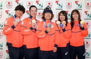 帰国後の記者会見でメダルを掲げるスノーボードの(左から)木俣椋真、木村葵来、長谷川帝勝、村瀬心椛、深田茉莉=22日午後、成田空港