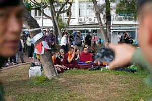 火災が起きた高層住宅近くで追悼の祈りをささげる人々。手前は周囲を警戒する警察官=2日、香港(共同)
