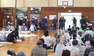 訓練で集まった住民に避難の際の注意点を呼びかける消防団員ら=6月6日、粟島浦村内浦集落