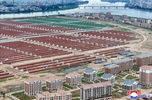 中朝国境の鴨緑江(奥)に面して建てられた住宅と建設中の大規模温室農場。1日に北朝鮮の金正恩朝鮮労働党総書記が視察した=北朝鮮北西部・新義州(朝鮮中央通信=共同)
