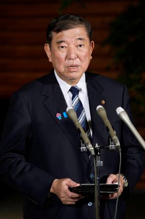 記者団の取材に応じる石破首相。夏の参院選公約を巡り、物価高対策として一律2万円の給付を掲げる考えを示した=13日午後、首相官邸