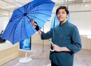 自身が開発した傘を広げるマーナの谷口諒太さん。「まさか自分の人生で傘のデザインをするとは思わなかった」と話す=東京都墨田区