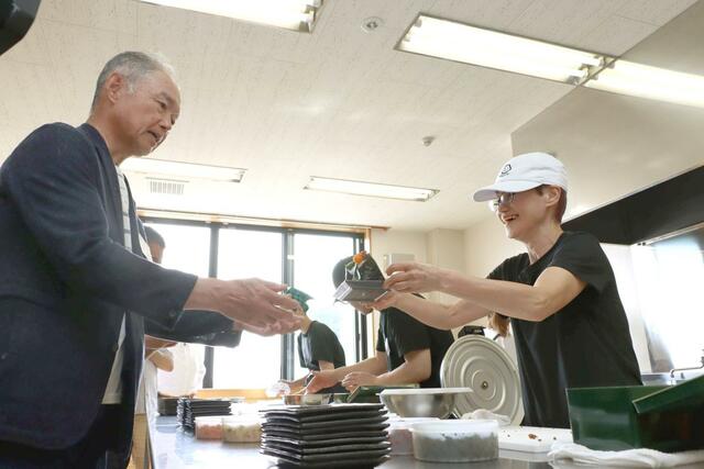 関川村の人たちにおにぎりを振る舞った右近由美子さん(右)=関川村下関