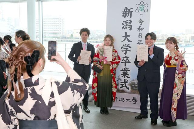記念撮影する新潟大の卒業生。４月からは、それぞれの道を歩む＝３月２４日、新潟市中央区