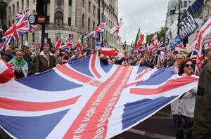 16日、ロンドンで極右活動家が主催したデモに参加し、英国旗を広げる人たち(共同)
