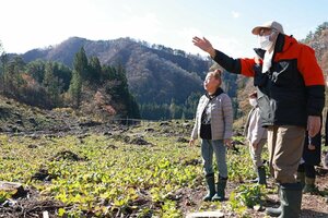 赤カブの栽培現場を訪れ、生産者の板垣喜美男さん(右)から説明を受けるツアー参加者=村上市荒川