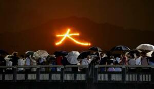 京都の伝統行事「五山送り火」が行われ、夜空に浮かび上がった文字を見る人たち=16日夜、京都市