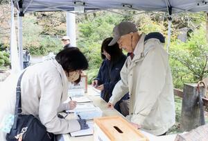 拉致問題の解決へ署名を呼びかけた大沢昭一さん（右）＝３日、弥彦村