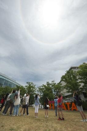 「日暈（ひがさ）」を撮影する観光客ら＝１８日、新潟市中央区