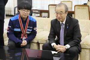 花角英世知事(右)と自身がプレーしたぷよぷよの動画を見る山田明宙さん=県庁