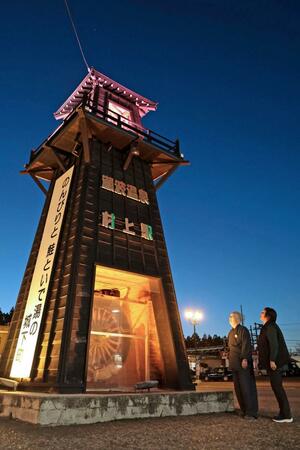 更生保護のシンボルカラーの黄色いライトで照らされたＪＲ村上駅前の歓迎塔＝１３日、村上市田端町