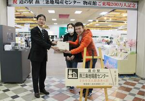200万人目の来場者となり、鈴木力・燕市長(左)から記念品などを受け取る来場者=三条市須頃1