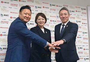 ポーズをとるアイスホッケー女子日本代表の大久保智仁新監督(右)と、久保英恵新コーチ(中央)ら=19日、東京都内