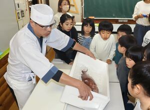 魚がさばかれる様子を真剣に見つめる栃窪小の児童=南魚沼市栃窪