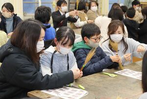 わらでほうきを作った刈羽小5年生と保護者ら=刈羽村割町新田