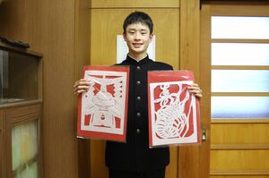 下げ紙を手に「小学生にも参加してもらうなどして、今後もこの活動が続くといい」と語る男子生徒=佐渡市水津