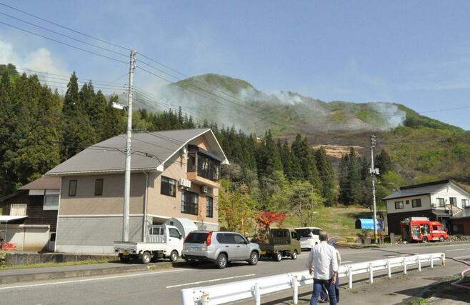山のカヤを焼いて立ち上る煙=26日、魚沼市赤土