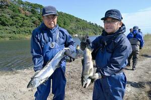 今季初となる漁で取れたサケを持つ木戸川漁協の組合員ら=23日午前、福島県楢葉町の木戸川