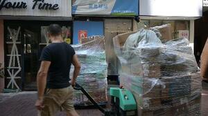 香港の街中に設置された宅配便の引き取り拠点の前で、山積みの荷物を運ぶ作業員=10月2日