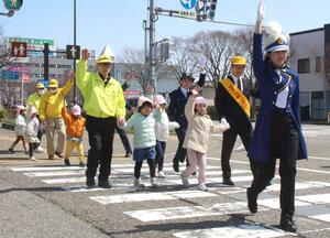 出発式の後、手を上げて横断歩道を渡る園児ら=4月5日、新潟市中央区