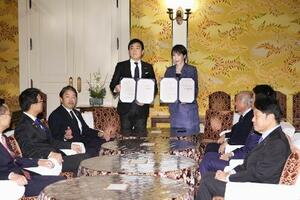 18日、国会内で会談し「年収の壁」引き上げを巡る合意書を手にする高市早苗首相(奥右)と国民民主党の玉木雄一郎代表(同左)