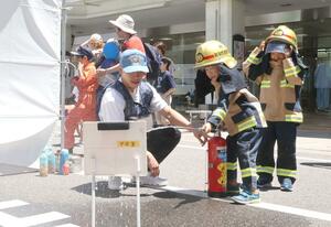 消防士になりきって消火活動を体験する子どもたち＝３０日、新潟市中央区万代１