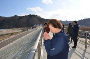 　田老地区の新たな防潮堤の上で、黙とうする元田久美子さん＝岩手県宮古市