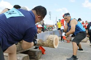 全力でのこぎりを引いて丸太を切るタイムを競った「全日本丸太早切選手権」=8月11日、長岡市三島中条