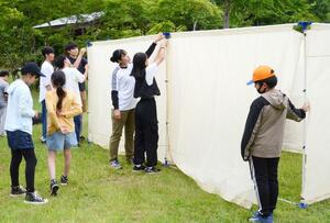 避難所で使う間仕切りを組み立てる小学生と津南中等教育学校の生徒=津南町上郷寺石