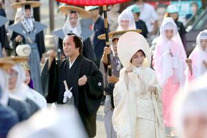 多くの観客に見守られながら歩調を合わせて歩いた花嫁と花婿=7日、阿賀町津川