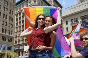 29日、米ニューヨークでの性的少数者のパレードで、虹色の旗を持ち抱き合う参加者(共同)