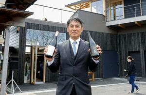 福島県富岡町の「とみおかワイナリー」で、自社のワインを手にする遠藤秀文さん=4月