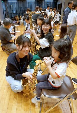 音楽団体の団員らから指導を受け、楽器を試奏する子どもたち=上越市下門前