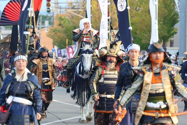 １００回目の謙信公祭で上杉謙信役を務め、沿道の観客に笑顔で手を振る松平健さん＝２３日、上越市