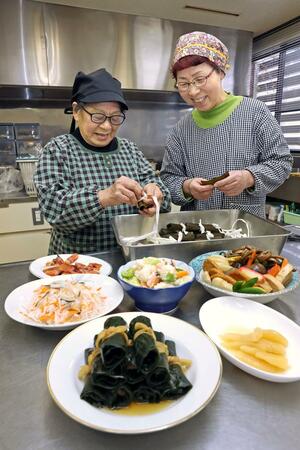 鮭の中骨が入った昆布巻きを作る佐藤あさのさん(左)と大桃久子さん。手前の正月料理も含め、次の世代に伝えたいと願う=2024年12月、魚沼市吉田