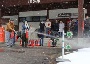 長野県と本県にまたがる宿泊施設などの外国人オーナーらを対象に、消火器の使い方などを学んだ防火講習会＝１２月１０日、長野県飯山市斑尾高原の「まだらお高原　山の家」