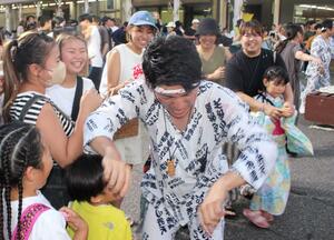 女性が「たたき地蔵」と声をかけ、男性をたたく場面も見られた=6月29日、魚沼市小出地区中心街