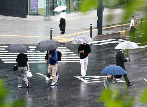 梅雨入りが発表された１０日、ＪＲ新潟駅前の交差点を傘を差して歩く人たち＝新潟市中央区
