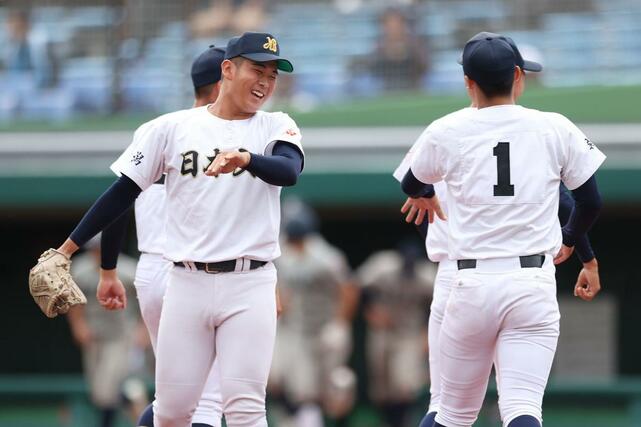 敦賀気比－日本文理　９回途中から登板した日本文理の室橋琉翔（左）がエース染谷崇史とタッチを交わす＝富山市民球場