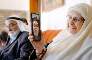 釈放後エジプトに移送されたアブドルジャワド・シャマスネさんとテレビ電話で話す母ハリマさん。左は父ユセフさん=10月、ヨルダン川西岸カタンナ(共同)