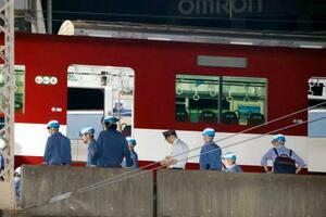 　脱線した近鉄京都線の車両付近で作業する人たち＝３０日午前０時４６分、京都市