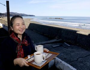波打ち際にほど近い谷浜海岸コーヒーのウッドデッキに立つ浅石まみさん＝上越市長浜