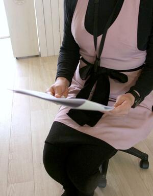 裁判資料を手にする被害女性=新潟市中央区