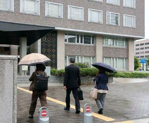 解雇無効の仮処分申し立てのため、札幌地裁に入る専門学校に勤めていた男性教員(中央)ら=30日午前