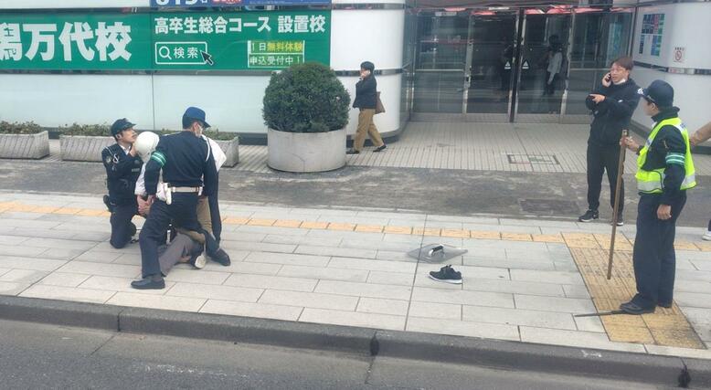警察に確保される男＝１６日、新潟市中央区万代４