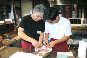 開店前の飲食店で、料理長から下ごしらえを学ぶミャンマー人男性=燕市吉田下中野