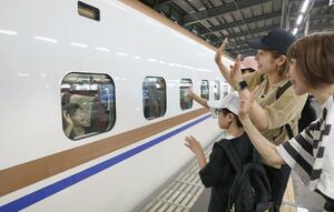 新幹線の発車前に別れを惜しんで手を振る人たち=8月16日、JR新潟駅
